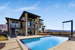 Rear view of property with a mountain view, stucco siding, a balcony, and a patio area