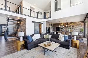 Living area with a barn door, brick wall, wood finished floors, a high ceiling, and recessed lighting