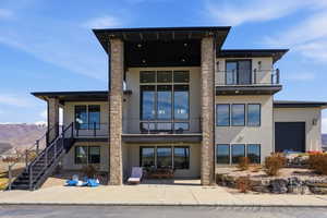 Rear view of property with stucco siding, a mountain view, outdoor dining space, and a balcony