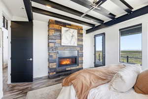 Bedroom with access to exterior, wood finished floors, and a stone fireplace