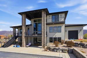 Rear view of property with stucco siding, a mountain view, and a balcony