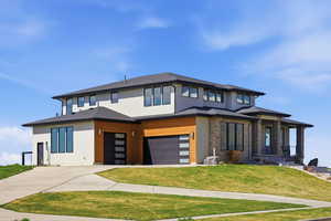 Prairie-style house featuring a front yard, driveway, stucco siding, and an attached garage