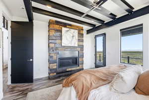 Bedroom featuring access to outside, wood finished floors, and a stone fireplace