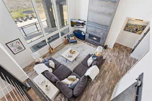 Living room with a fireplace, wood finished floors, and a high ceiling