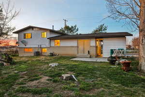 Back of house featuring a lawn, brick siding, and a patio