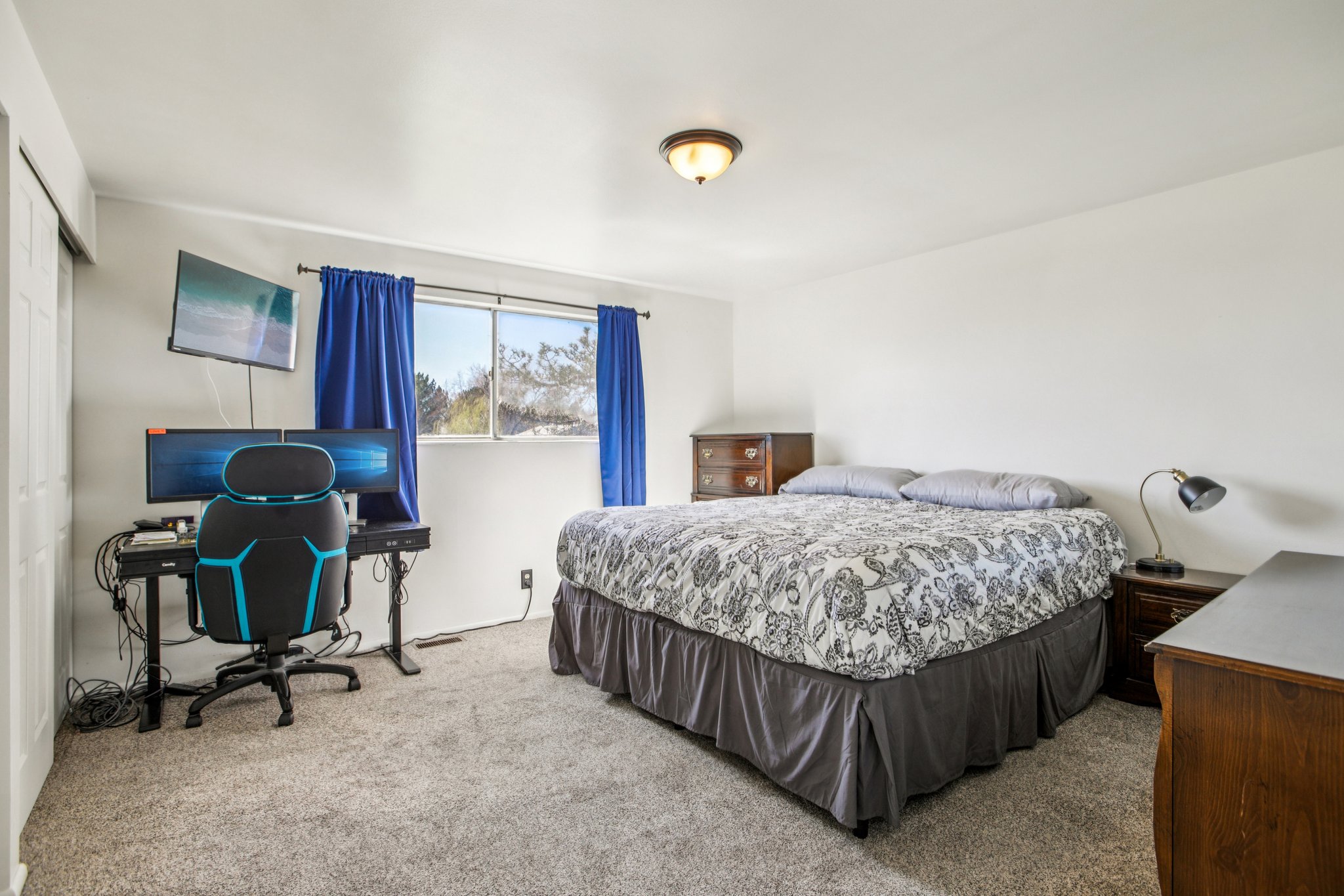 Bedroom featuring light colored carpet, a closet, and a desk