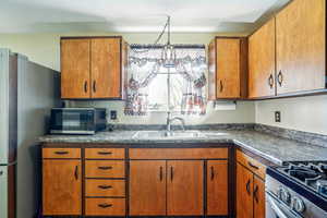 Kitchen with wood finish cabinets, dark countertops, and stainless steel appliances