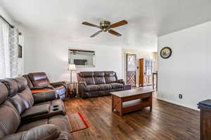 Living area with dark wood-style floors and a ceiling fan