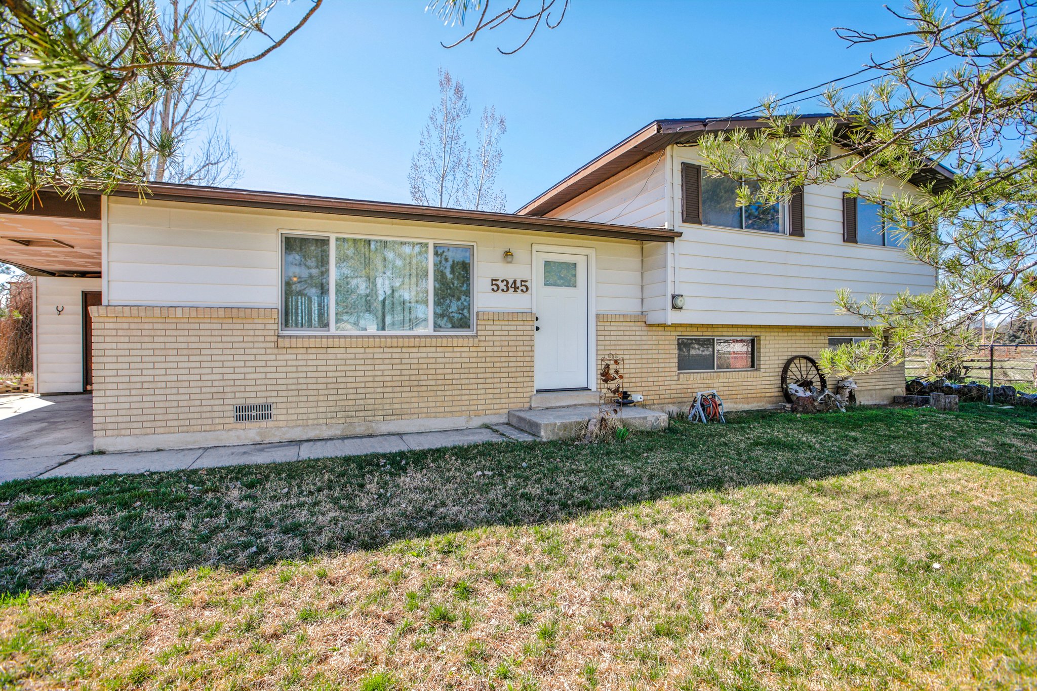 Split level home featuring brick siding, crawl space, and a carport