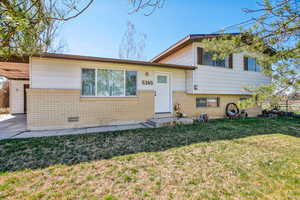 Split level home featuring brick siding, crawl space, and a carport