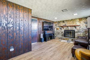 Living area with a fireplace, light wood-style flooring, and wood walls
