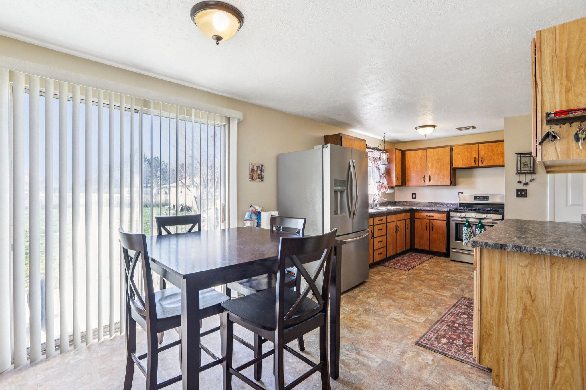 Kitchen with dark countertops, wood finish cabinetry, stainless steel appliances, and stone finish floors