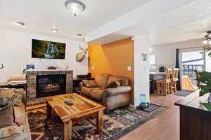 Living area with ceiling fan, a fireplace, wood finished floors, and a textured ceiling