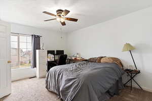 Carpeted bedroom with a ceiling fan and a desk