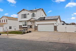 Traditional-style house featuring a gate, brick siding, solar panels, and a garage
