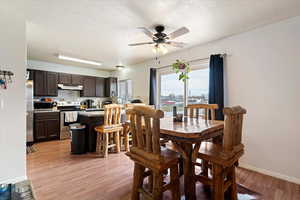 Dining space featuring light wood-style flooring, ceiling fan, and a textured ceiling
