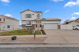 View of front of house featuring a gate, roof mounted solar panels, brick siding, and a garage