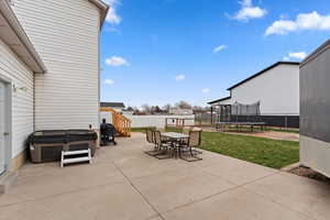 Fenced backyard featuring a trampoline, a patio area, outdoor dining space, and grilling area