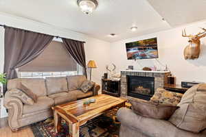 Living area with wood finished floors, a fireplace, and a textured ceiling