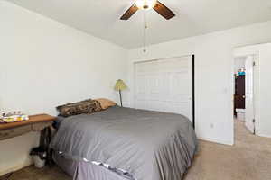 Carpeted bedroom featuring a closet and ceiling fan