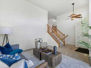 Living room with carpet floors, a ceiling fan, and a high ceiling