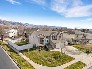 Traditional-style home featuring a residential view, driveway, a shingled roof, a mountain view, and an attached garage