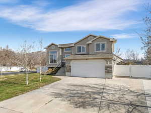 View of front facade featuring a gate, driveway, an attached garage, and stucco siding