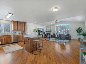 Kitchen featuring wood finish cabinets, open floor plan, light stone countertops, a fireplace, and a center island