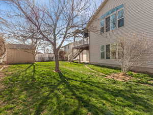 View of grassy yard with a deck and an outdoor structure
