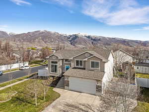 View of front of house with a garage, a shingled roof, concrete driveway, and a mountain view