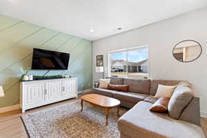 Living room with an accent wall, light wood-style floors, and recessed lighting