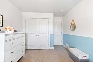 Bedroom with light carpet and a closet
