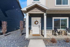 Doorway to property featuring covered porch, board and batten siding, and stone siding