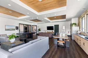 Living area with dark wood-style floors, recessed lighting, and a wooden tray ceiling