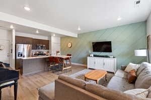 Living area featuring light wood finished floors, recessed lighting, and an accent wall