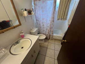 Full bath with vanity, shower / bath combo, tile walls, and light tile patterned flooring