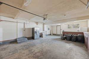 Garage featuring stainless steel refrigerator with ice dispenser and freestanding refrigerator