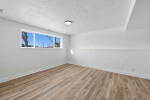 Empty room featuring light wood-style flooring and a textured ceiling