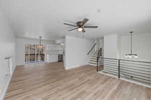 Unfurnished living room with a chandelier, a ceiling fan, and light wood-type flooring