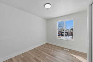 Empty room featuring light wood-type flooring and a textured ceiling