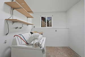 Laundry area with washer / clothes dryer and unfinished concrete flooring