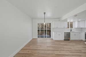 Bar area with white cabinetry, stainless steel dishwasher, decorative light fixtures, and light wood-style flooring