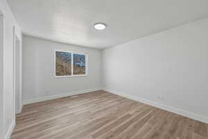 Unfurnished bedroom featuring light wood-type flooring, a textured ceiling, and a closet
