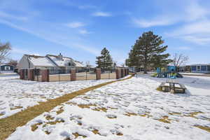 Yard layered in snow featuring a playground and a residential view