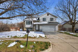 Split level home featuring brick siding, a garage, and concrete driveway