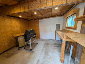 Miscellaneous room with concrete floors, electric panel, recessed lighting, a workshop area, and wooden walls