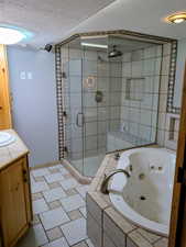 Bathroom with vanity, a textured ceiling, a jetted tub, and a stall shower