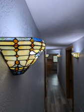 Hallway featuring a textured wall and dark wood-style floors