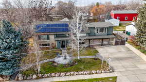 View of front of home featuring brick siding, an attached garage, concrete driveway, and roof mounted solar panels