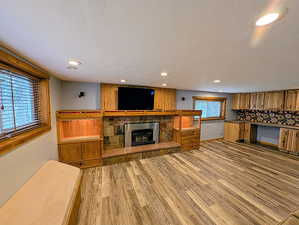 Unfurnished living room with a fireplace, light wood-type flooring, recessed lighting, and a textured ceiling